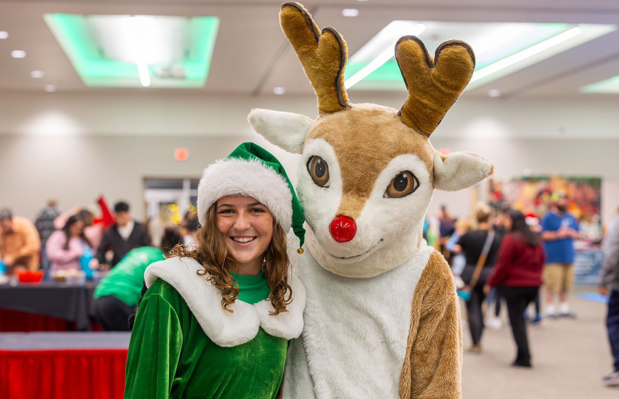 A smiling elf posing with a reindeer at Christmas in Portland