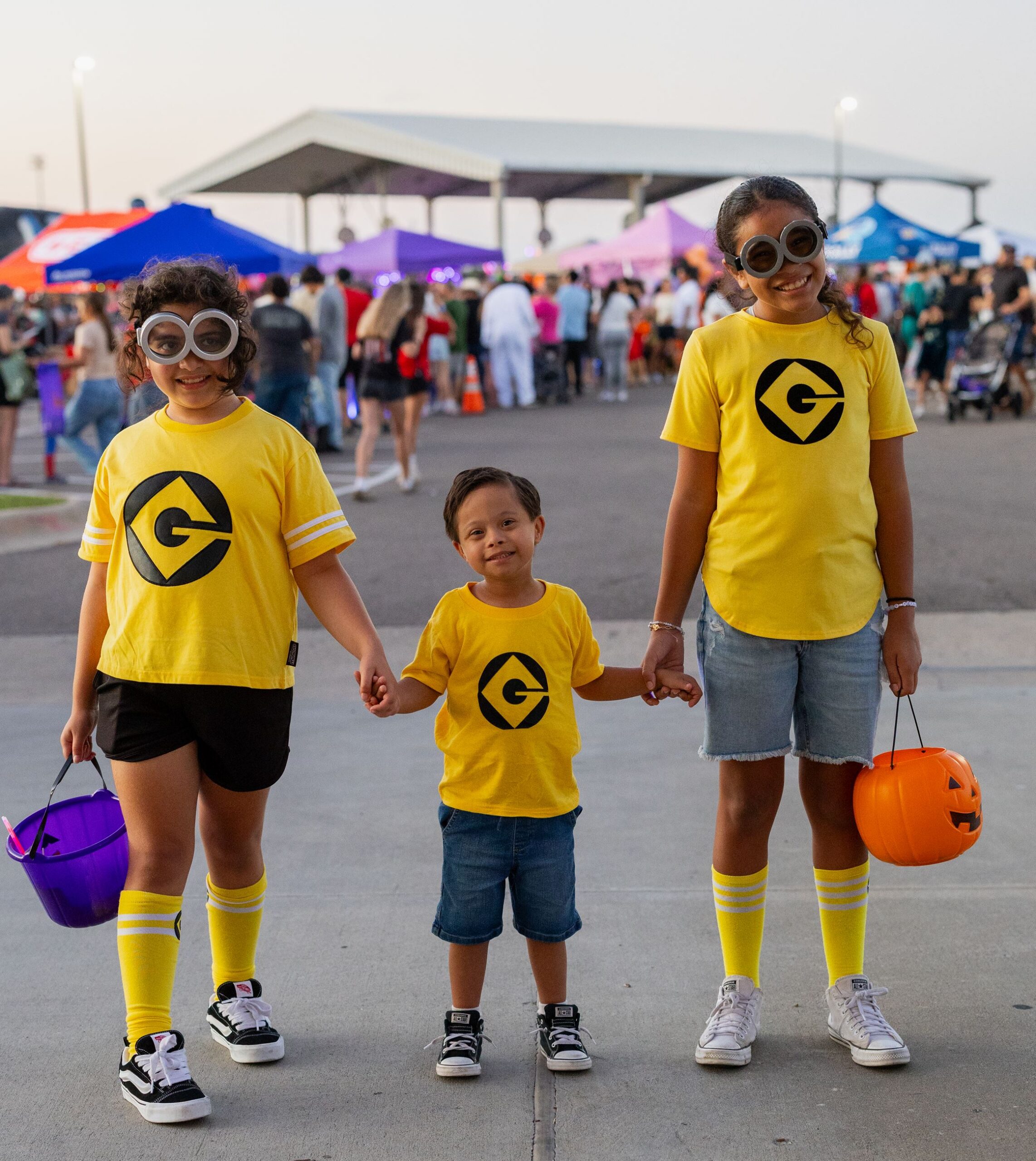 Three kids dressed as minions holding hands at Boo Bash