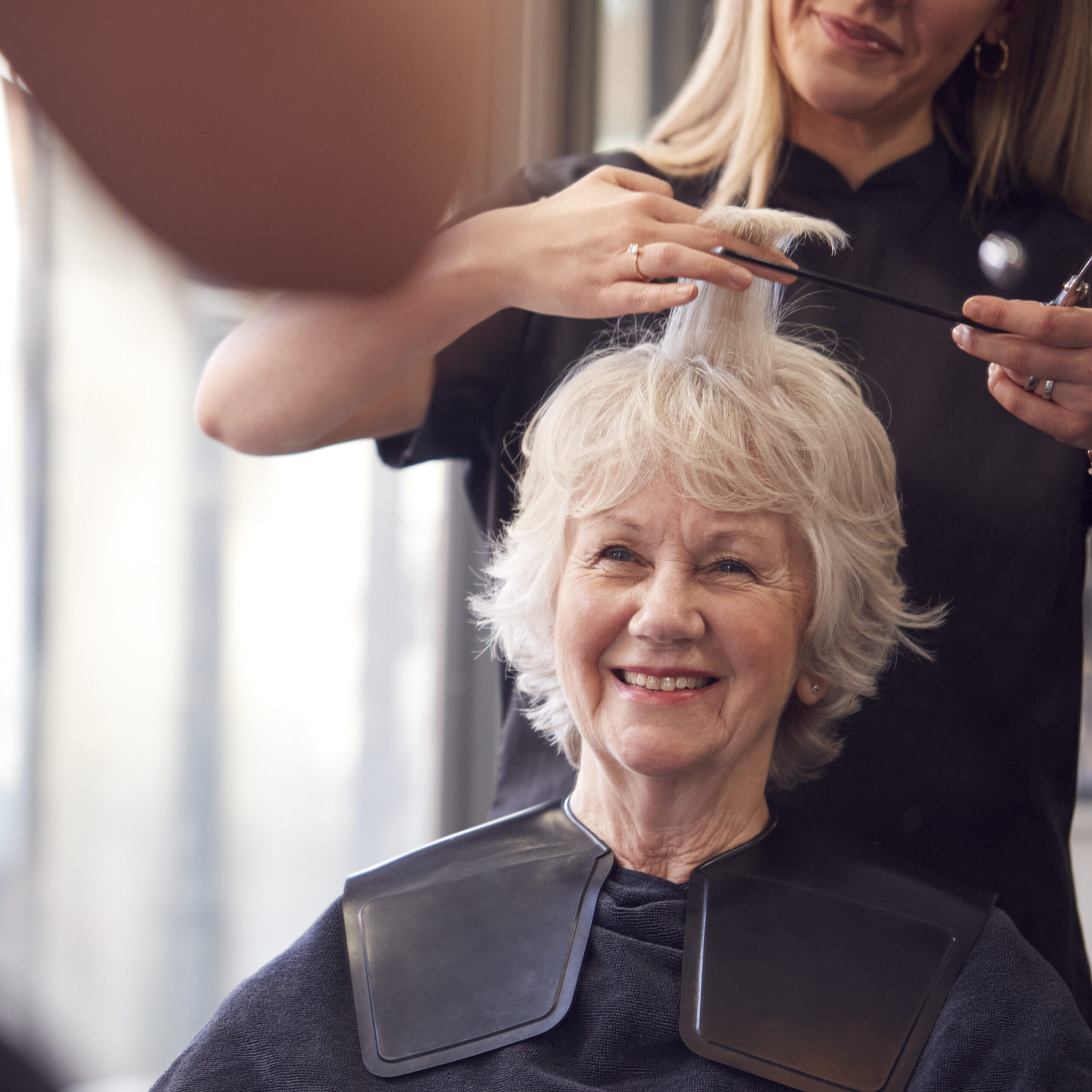 Woman Having Hair Cut By Female Stylist In Salon